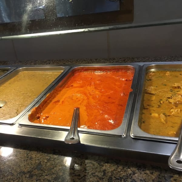 Three buffet trays of Indian food, including a vibrant orange curry, at India Grill.